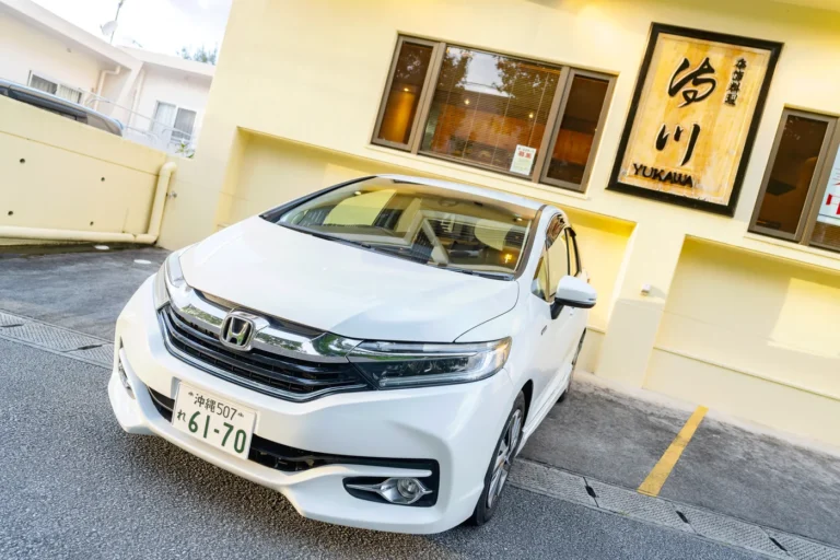 Honda Fit Hybrid photographed in front of the Okinawa Rent-a-Car Shuttle Yukawa